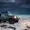 A 4x4 vehicle driving through snow in a mountainous winter landscape at dusk.